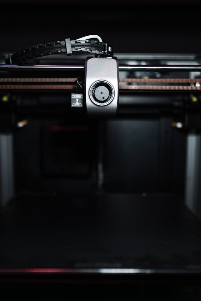 Close-up of a high-precision industrial 3D printer nozzle in a dark setting, showcasing advanced technology.